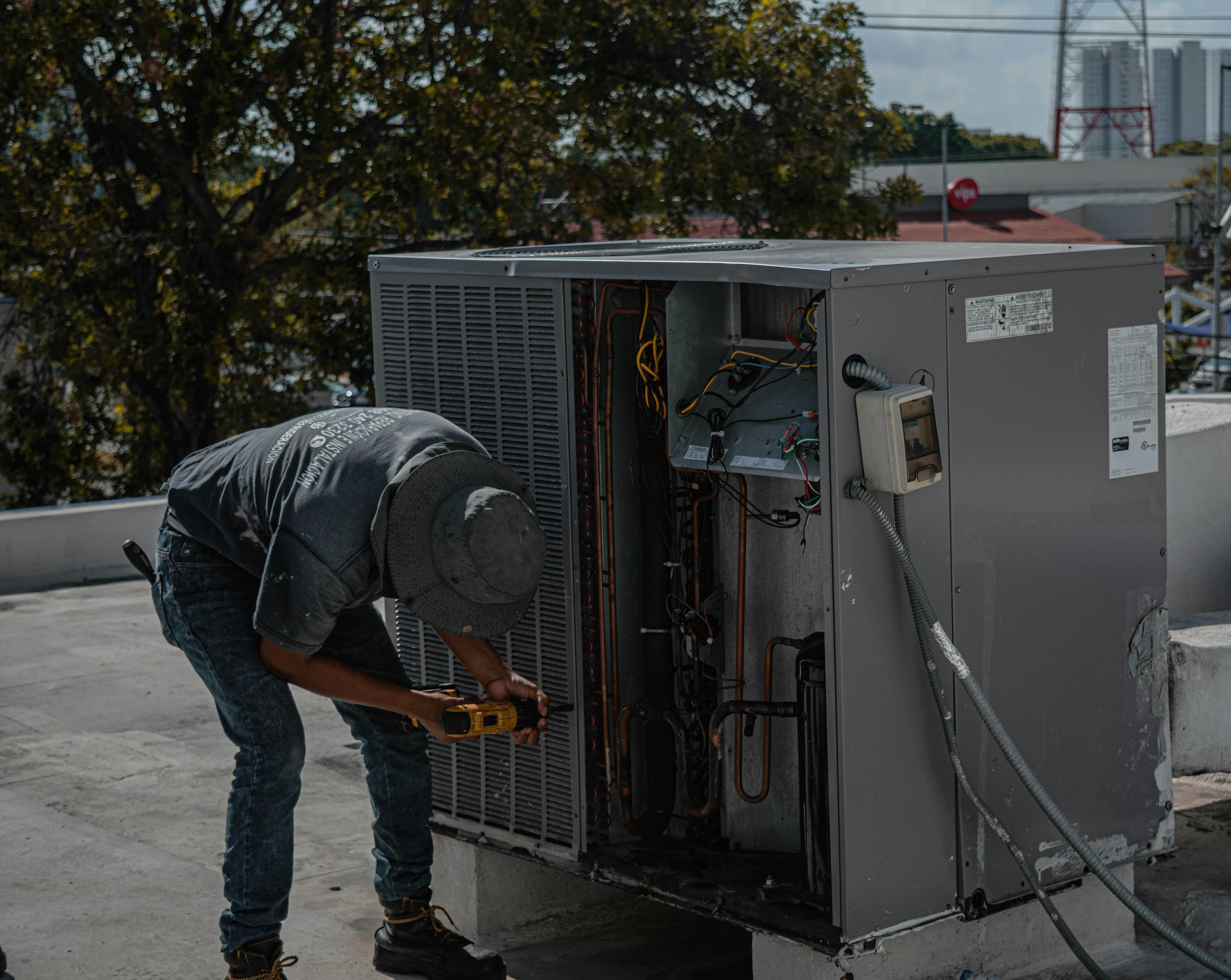 HVAC professional servicing large outdoor AC unit on sunny Long Island home